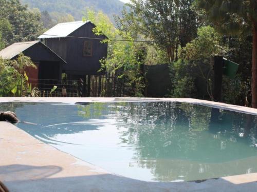 una piscina de agua con una casa en el fondo en Sabie Gypsy's Backpackers, en Sabie