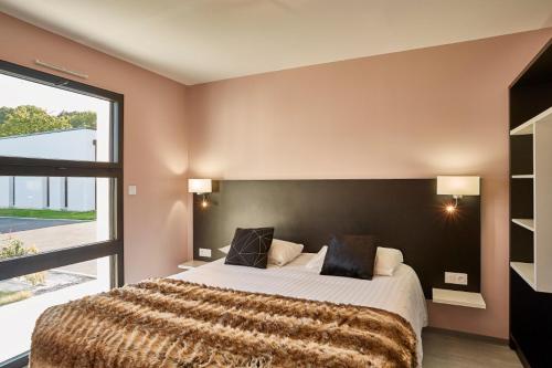 een slaapkamer met een groot bed en een groot raam bij Village by logis in Le Gâvre
