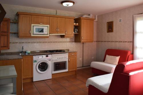 a kitchen with a stove and a washing machine at Apartamentos Rurales la Taberna in Matienzo