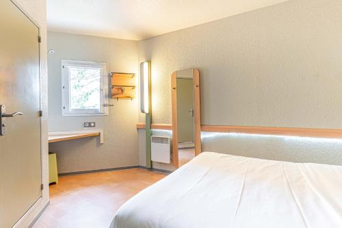 Habitación pequeña con cama y ventana en Fasthotel Cleon Rouen Sud en Cléon
