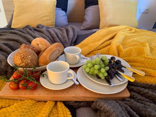 a tray with two cups and plates of food on a bed at eifel24, neu, modern mit Dachterrasse in Schwirzheim
