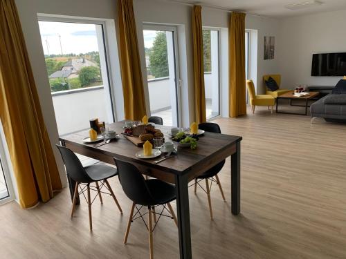 a dining room with a table and chairs and a living room at eifel24, neu, modern mit Dachterrasse in Schwirzheim