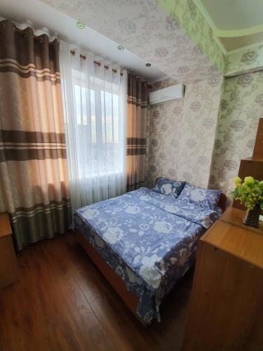 um quarto com uma cama e uma janela com cortinas em Genny aparment in the center city em Bishkek