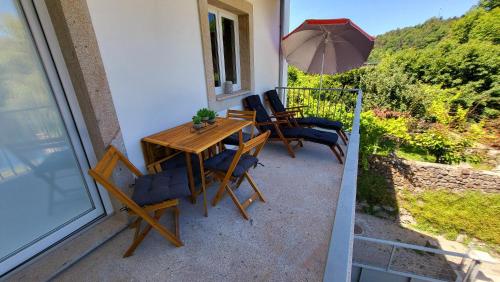 a table and chairs on a balcony with an umbrella at Casa Barca Velha in Ponte da Barca