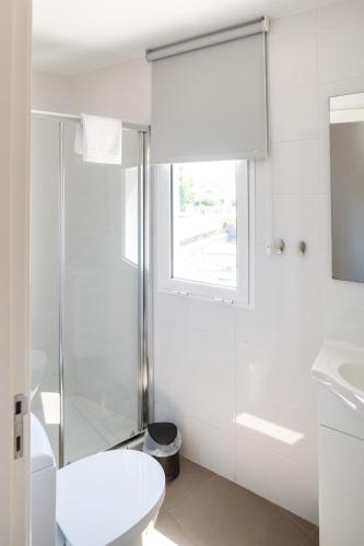 a white bathroom with a shower and a toilet at Casa das Rosas - Roses House in Miranda do Corvo