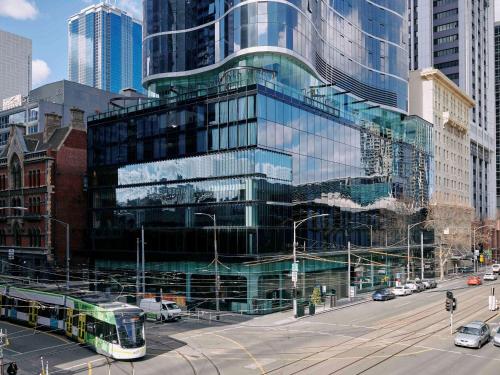 a bus driving down a street in a city at Movenpick Hotel Melbourne On Spencer in Melbourne