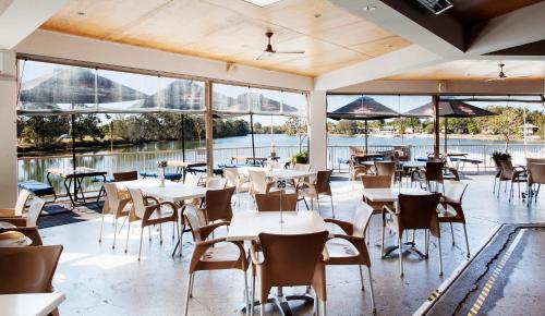 a restaurant with tables and chairs and large windows at Nightcap at Northern Grounds in Maroochydore