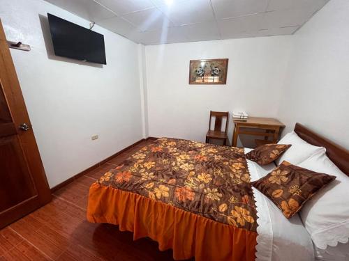 a bedroom with a bed and a tv on the wall at Hospedaje Familiar Laos in Oxapampa