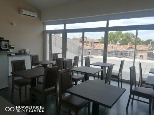 SQUARE HOTEL في نيم: غرفة طعام بها طاولات وكراسي ونافذة كبيرة