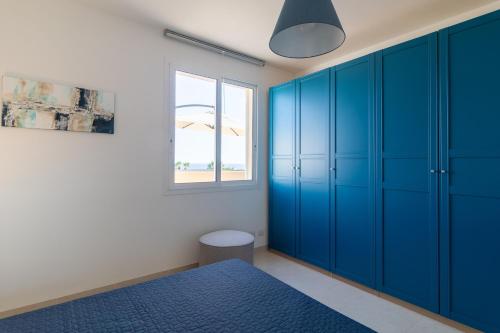 1 dormitorio con armarios azules y ventana en Brezzadisudest, en Marina di Ragusa