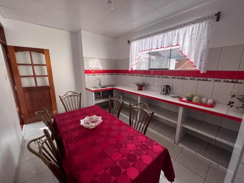 a dining room with a red table and a kitchen at Hospedaje Familiar Laos in Oxapampa