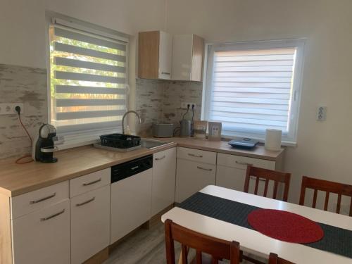 a kitchen with white cabinets and a table with a tableablish at Arvisura Vendégházak family friendly transit apartments in Zsombó
