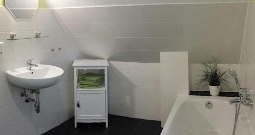 a white bathroom with a sink and a tub at Ferienhaus Strandräuber in Marienfelde