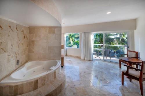 a large bathroom with a tub and a table at Viva Azteca by Wyndham, A Trademark All Inclusive Resort in Playa del Carmen