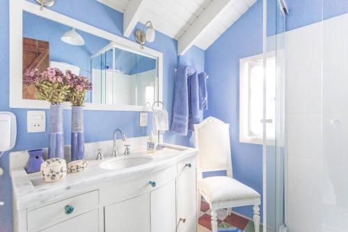 uma casa de banho azul com um lavatório e um espelho em Morada das Flôres em Porto Alegre