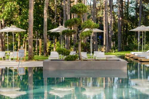 a swimming pool with white chairs and umbrellas at Ensana Aquahouse in St. St. Constantine and Helena