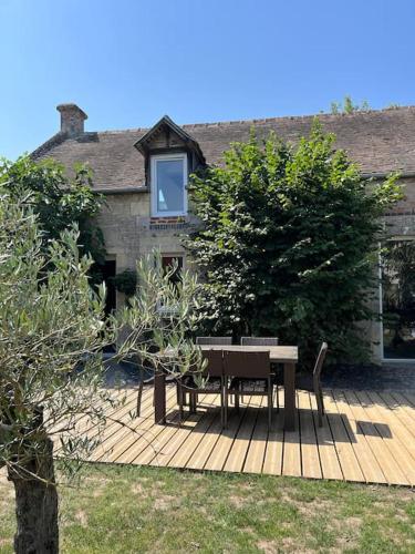 een tafel en stoelen op een houten terras bij Charmante maison du XVIII en pierre rénovée in Colleville-Montgomery