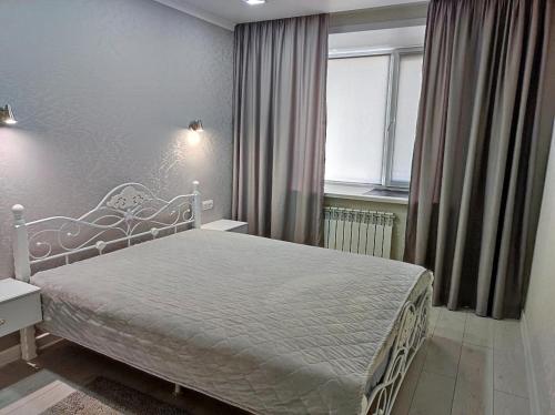 a bedroom with a white bed and a window at 2х комнатные апартаменты VIP на Назарбаева 44 in Pavlodar