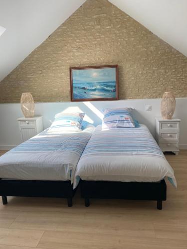een slaapkamer met 2 bedden op een zolder bij Charmante maison du XVIII en pierre rénovée in Colleville-Montgomery