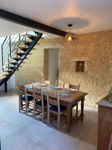 une salle à manger avec une table en bois et un mur en briques dans l'établissement Charmante maison du XVIII en pierre rénovée, à Colleville-Montgomery