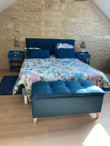 a blue bed in a bedroom with two tables at Charmante maison du XVIII en pierre rénovée in Colleville-Montgomery