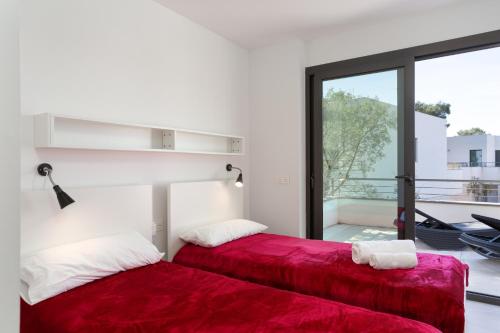 two beds with red sheets in a room with a window at 4 Bedroom Modern House, Llafranc, Costa Brava in Llafranc