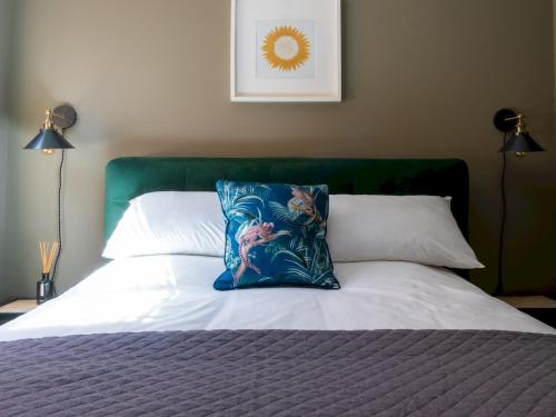 a bed with a blue pillow on top of it at Pass the Keys Elegant stylish home in historic town centre sleeps 3 in Moreton in Marsh