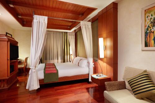 a bedroom with a bed with curtains and a couch at The Davis Bangkok in Bangkok