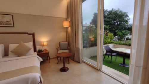 a hotel room with a bed and a sliding glass door at juSTa Rudra Resort & Spa in Kolād