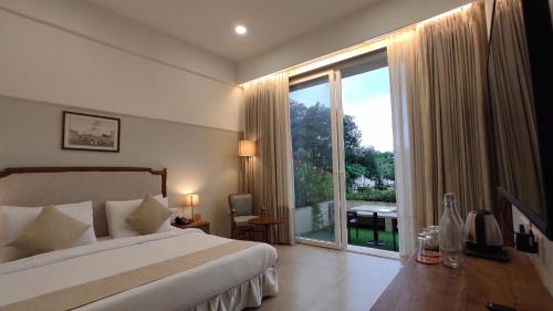 a hotel room with a bed and a large window at juSTa Rudra Resort & Spa in Kolād