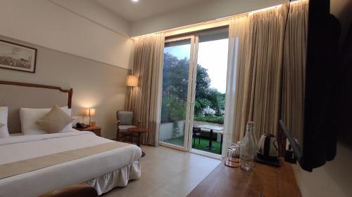a hotel room with a bed and a large window at juSTa Rudra Resort & Spa in Kolād