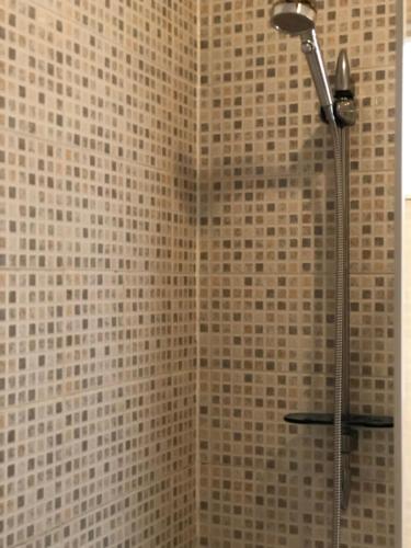 W łazience z wyłożoną kafelkami ścianą znajduje się prysznic. w obiekcie Admiral Guest House w Scarborough