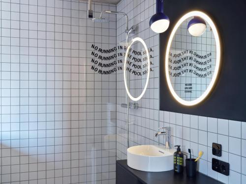baño con 2 espejos y lavamanos en STAYERY Frankfurt Sachsenhausen, en Frankfurt