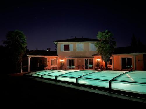 - une grande piscine en face d'une maison la nuit dans l'établissement Charmant logis neuf équipé/Piscine/SPA/Sauna/Gym, à Heyrieux