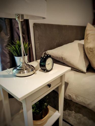 a table with a clock on it next to a bed at Hursley Rooms - The Dolphin in Winchester