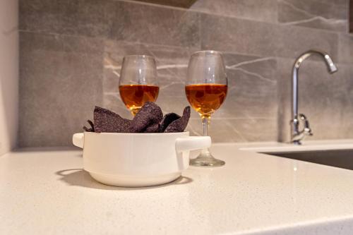 two glasses of wine on a kitchen counter with a bowl of food at Apt 27 CityLife Aruba in Oranjestad