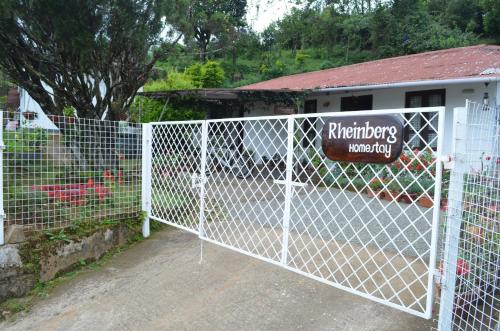 a white fence with a gate in front of a yard at Rheinberg Town Haus in Munnar
