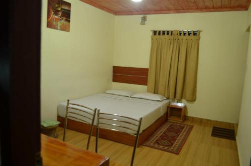 a small bedroom with a bed and a curtain at Rheinberg Town Haus in Munnar