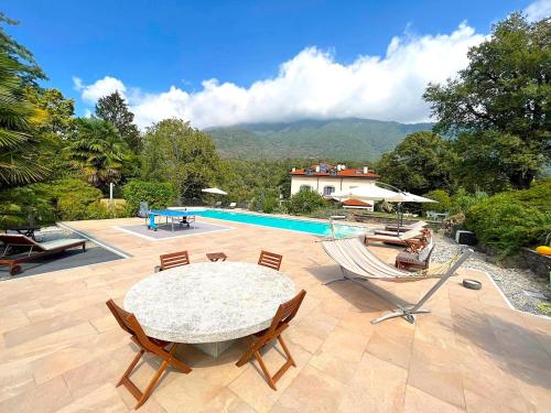 a patio with a table and chairs and a pool at The comfortable house with big pool in the center of Mergozzo in Mergozzo