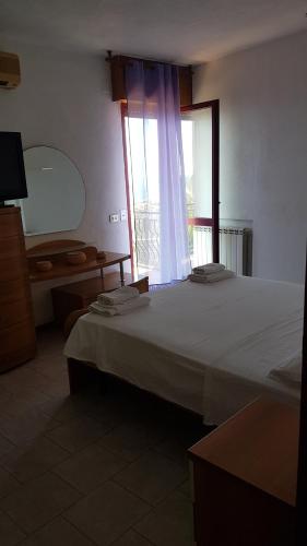 a bedroom with a large bed and a window at Camerota Basic Appartamenti in Lentiscosa