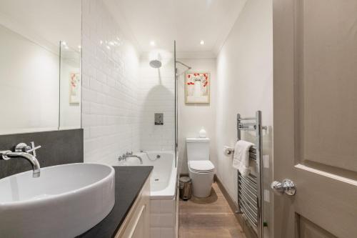 a white bathroom with a sink and a toilet at The Brunswick Oasis in London