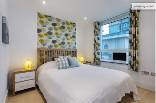 a bedroom with a large bed and a window at Veeve - Modernist Wharf in London