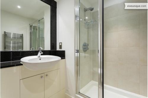 a bathroom with a sink and a glass shower at Veeve - Modernist Wharf in London
