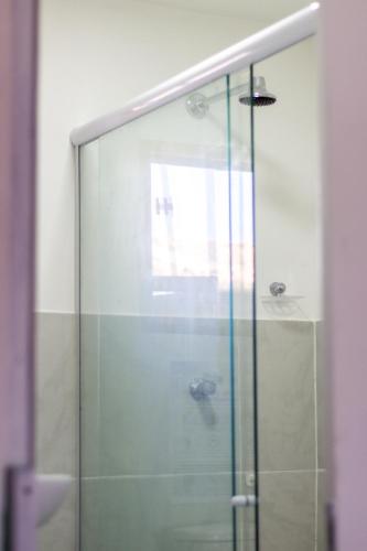 a shower with a glass door in a bathroom at Aloha Hostel Pinhões in Fortaleza
