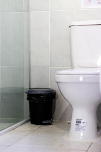 a bathroom with a toilet and a black trash can at Aloha Hostel Pinhões in Fortaleza