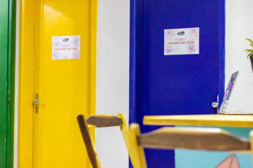 a blue door with two signs on it next to a table at Aloha Hostel Pinhões in Fortaleza