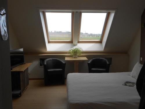フーフェルラントにあるb&b Kraaibergのベッド1台、椅子2脚、窓が備わる客室です。