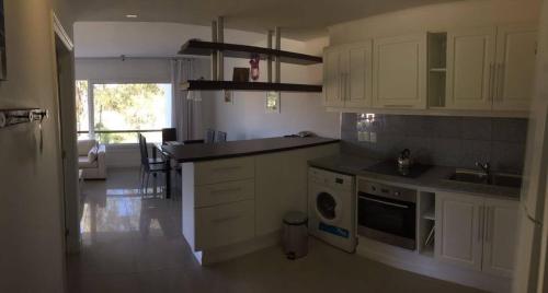 eine Küche mit weißen Schränken, einer Spüle und einem Geschirrspüler in der Unterkunft Green Park Hermosos Apartamentos Vista al Lago in Punta del Este