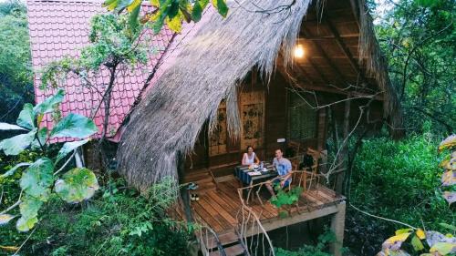 two people sitting on the deck of a house at Habarana Tree House Ambasewana Resort in Habarana