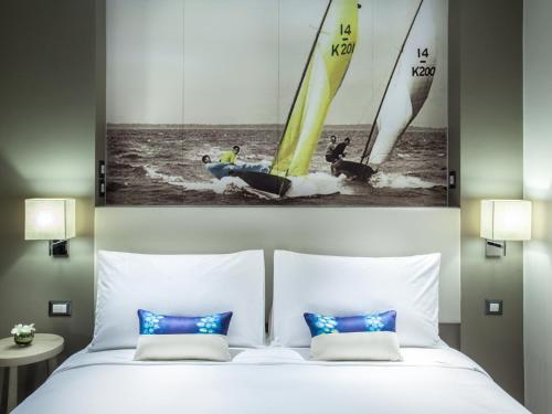 a bedroom with a bed with two sail boats in the water at Mercure Pattaya Ocean Resort in Pattaya Central